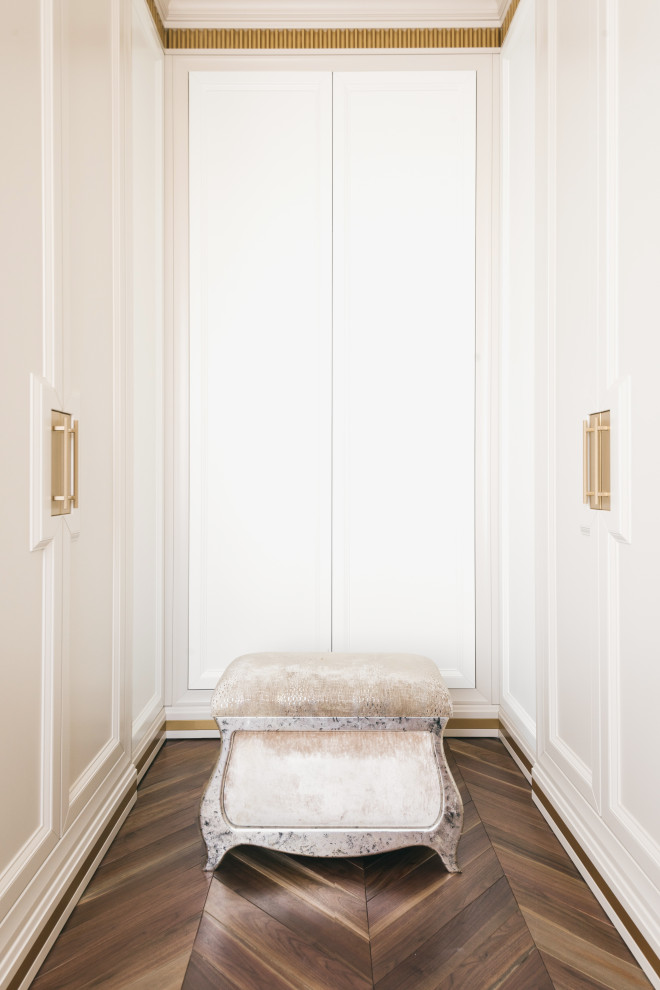 На фото: большая гардеробная комната в стиле неоклассика (современная классика) с фасадами с утопленной филенкой, бежевыми фасадами, темным паркетным полом и коричневым полом для женщин