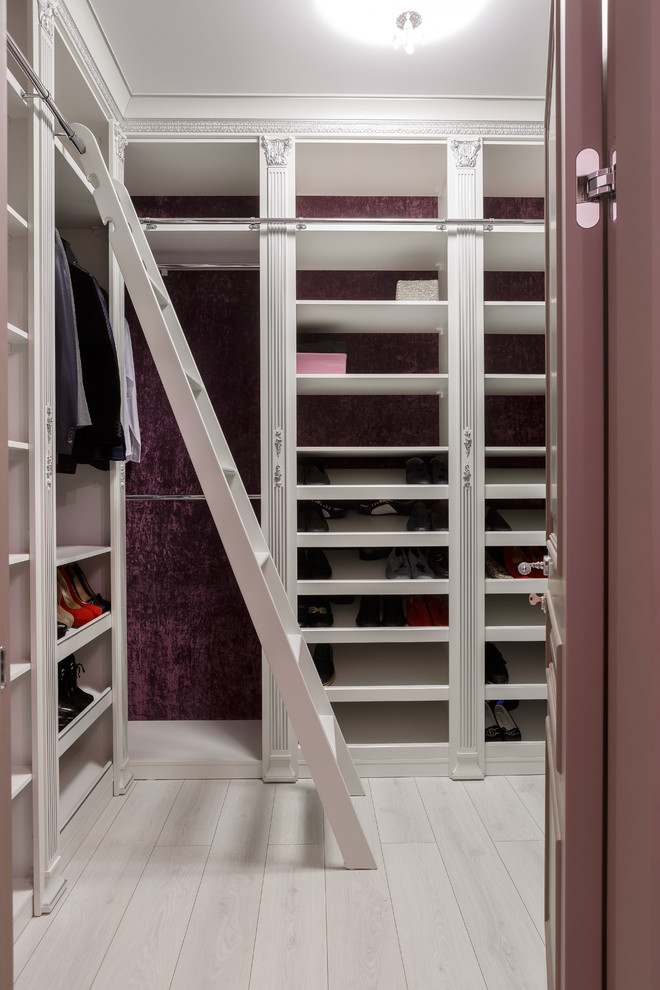 Ejemplo de armario vestidor unisex clásico renovado de tamaño medio con armarios con paneles con relieve, puertas de armario blancas, suelo de madera clara y suelo beige