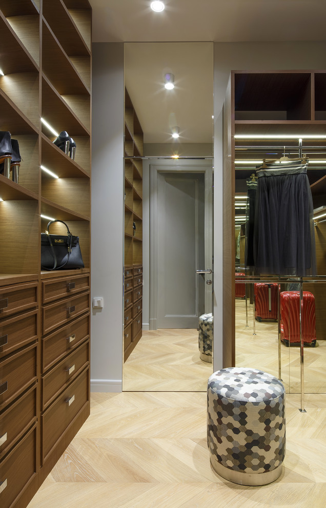 Photo of a classic gender neutral walk-in wardrobe in Moscow with recessed-panel cabinets, medium wood cabinets and light hardwood flooring.
