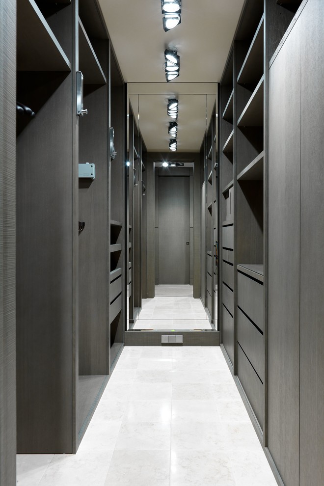На фото: гардеробная комната среднего размера, унисекс в современном стиле с плоскими фасадами, темными деревянными фасадами и белым полом