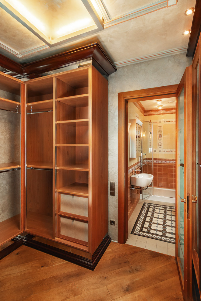 Идея дизайна: большая гардеробная комната унисекс в викторианском стиле с открытыми фасадами и оранжевым полом