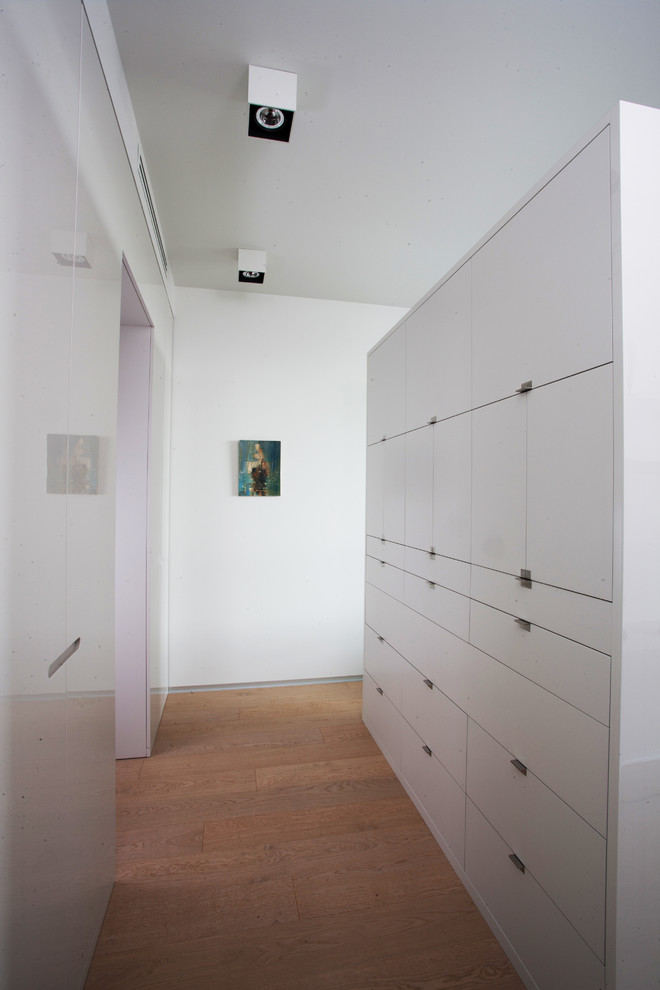Пример оригинального дизайна: гардеробная комната среднего размера в современном стиле с плоскими фасадами, белыми фасадами и светлым паркетным полом