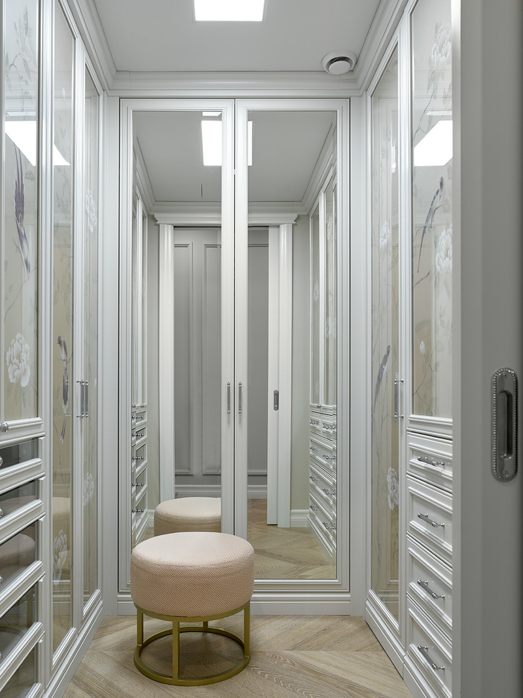 На фото: гардеробная комната унисекс в классическом стиле с белыми фасадами, светлым паркетным полом и бежевым полом с