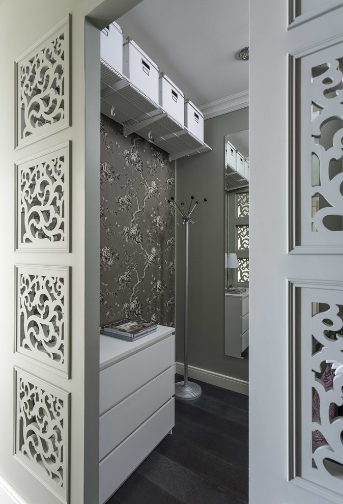 Small traditional gender neutral walk-in wardrobe in Moscow with flat-panel cabinets, white cabinets, dark hardwood flooring and black floors.