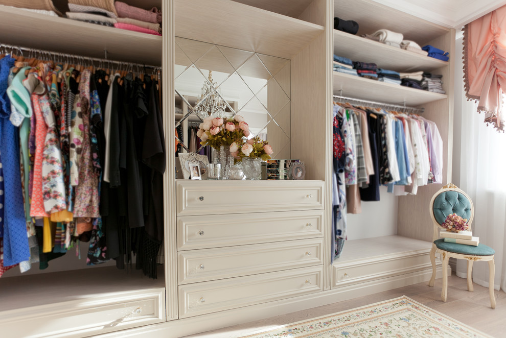 Diseño de vestidor unisex tradicional con armarios con paneles empotrados, puertas de armario beige, suelo de madera clara y suelo beige