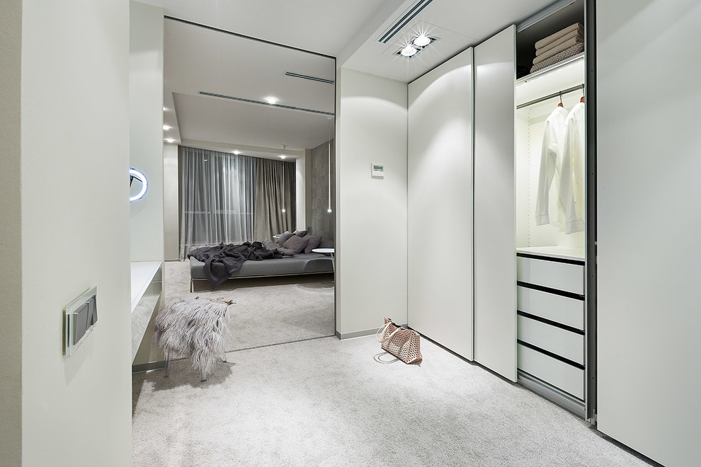 Immagine di una cabina armadio unisex contemporanea di medie dimensioni con ante lisce, ante bianche, moquette e pavimento grigio