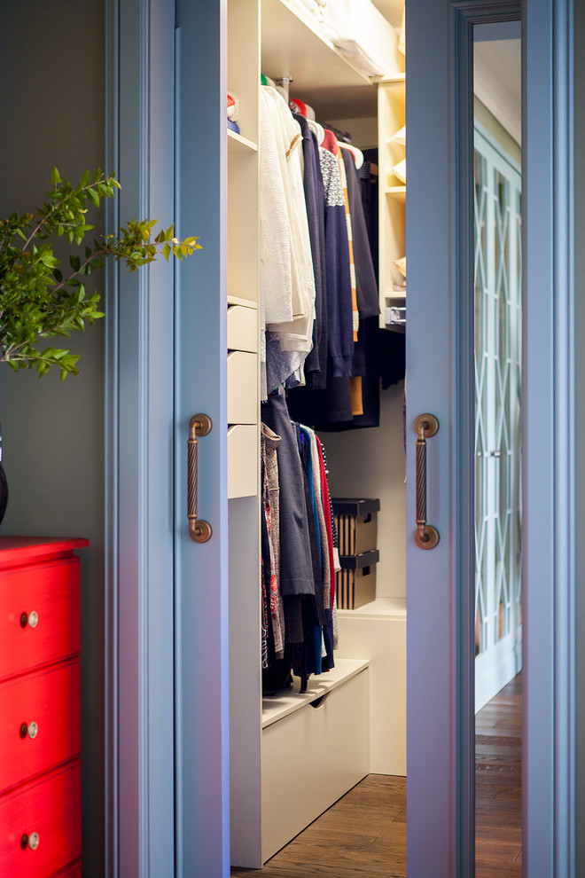 Imagen de armario vestidor unisex tradicional renovado con armarios con paneles lisos, puertas de armario blancas y suelo de madera oscura