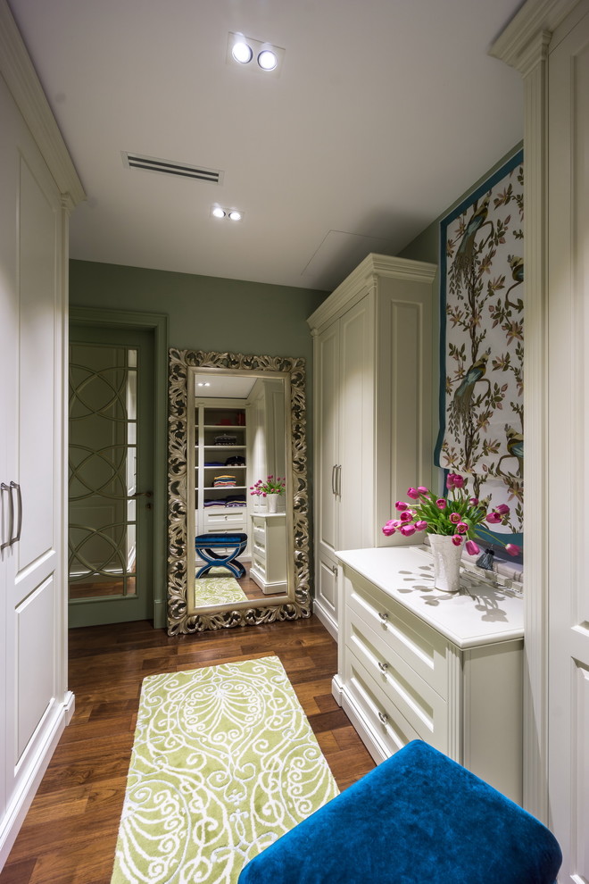 Inspiration for a medium sized traditional dressing room in Moscow with white cabinets and dark hardwood flooring.