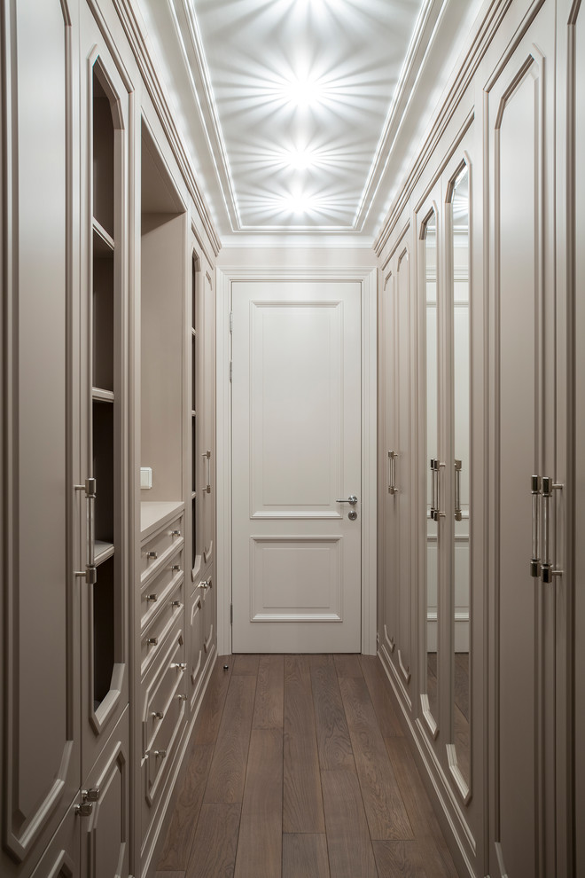 Стильный дизайн: гардеробная комната среднего размера в стиле неоклассика (современная классика) с бежевыми фасадами, темным паркетным полом и коричневым полом для женщин - последний тренд