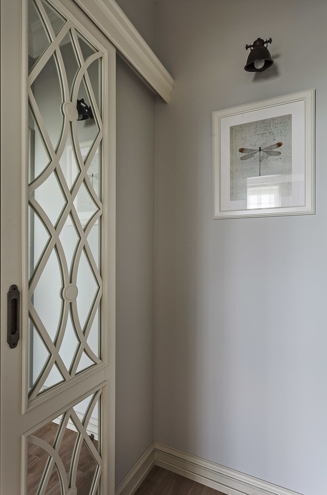 Ejemplo de armario vestidor unisex tradicional renovado pequeño con armarios con paneles con relieve, puertas de armario blancas, suelo laminado y suelo beige
