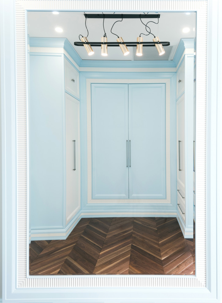 Großer Klassischer Begehbarer Kleiderschrank mit Schrankfronten mit vertiefter Füllung, blauen Schränken, dunklem Holzboden und braunem Boden in Moskau