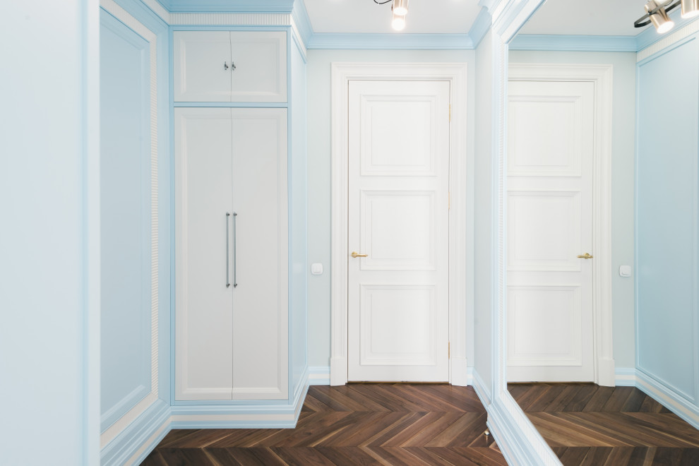 Стильный дизайн: большая гардеробная комната в стиле неоклассика (современная классика) с фасадами с утопленной филенкой, синими фасадами, темным паркетным полом и коричневым полом для мужчин - последний тренд