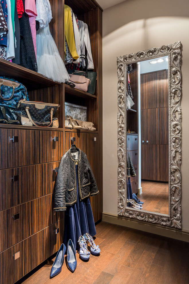 Photo of a walk-in wardrobe for women in Moscow with flat-panel cabinets and dark wood cabinets.