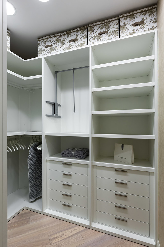 Ejemplo de armario vestidor unisex contemporáneo de tamaño medio con armarios con paneles lisos, puertas de armario blancas, suelo beige y suelo de madera clara