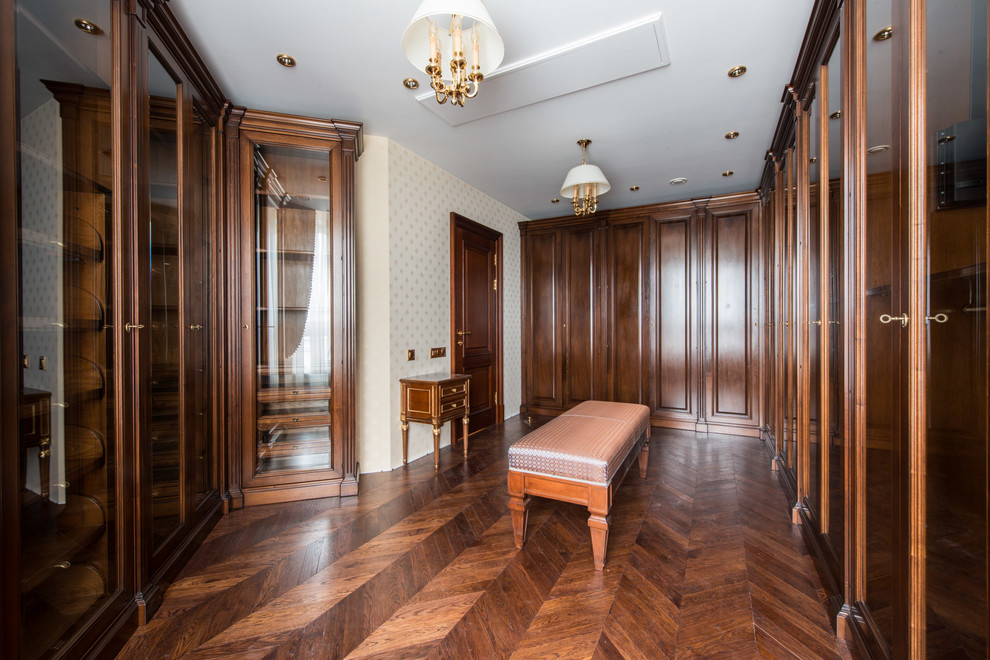 Foto de vestidor unisex clásico con puertas de armario de madera oscura y suelo de madera en tonos medios