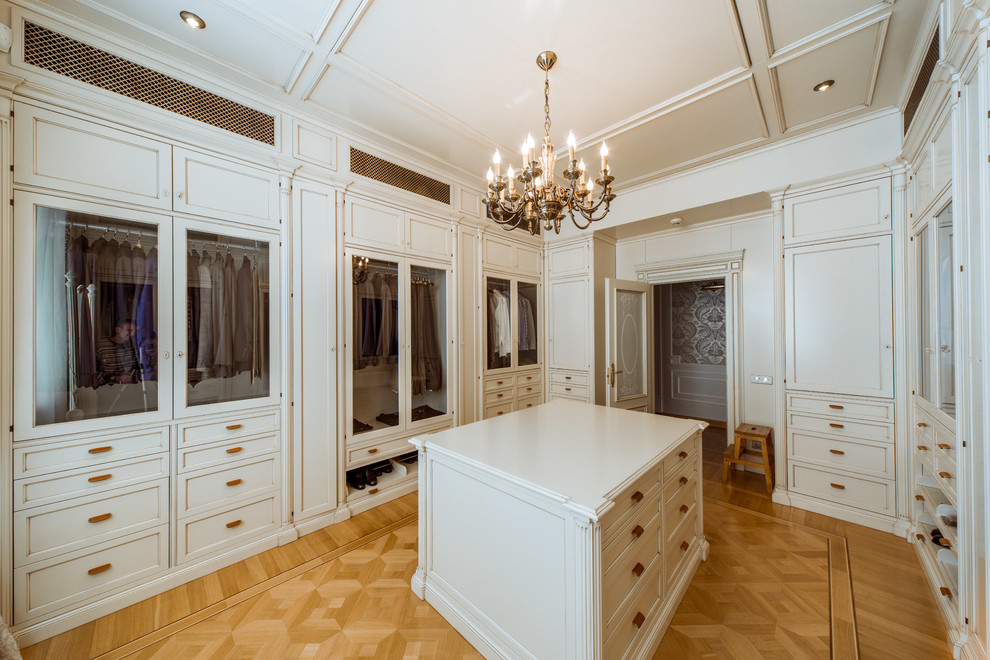 Свежая идея для дизайна: гардеробная комната унисекс в классическом стиле с фасадами с утопленной филенкой, белыми фасадами и паркетным полом среднего тона - отличное фото интерьера