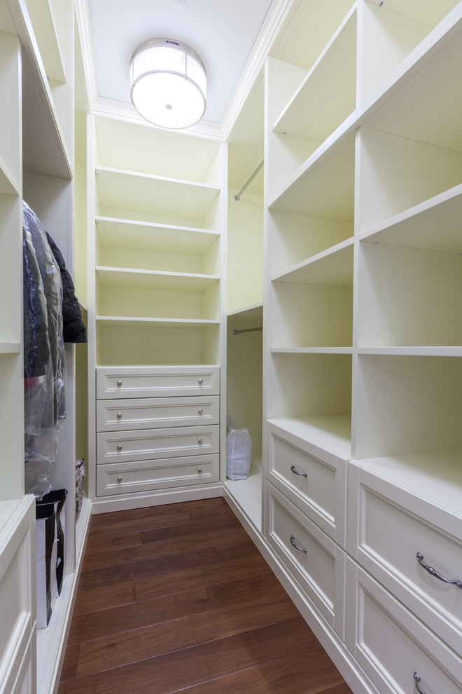 Modelo de armario vestidor unisex tradicional de tamaño medio con armarios abiertos, puertas de armario de madera clara, suelo de madera en tonos medios y suelo marrón