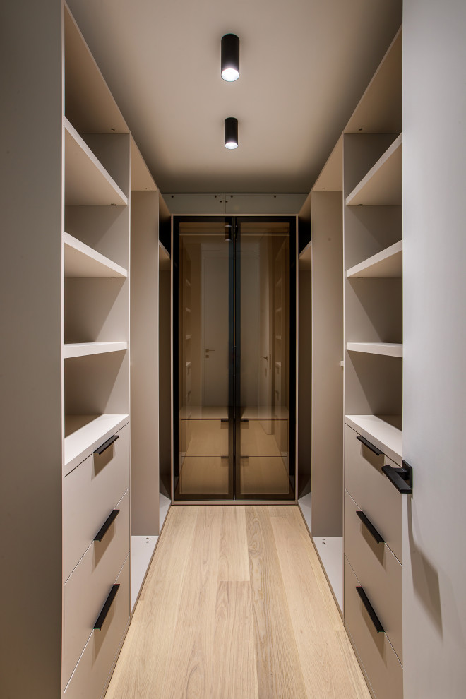 Свежая идея для дизайна: гардеробная комната унисекс в современном стиле с плоскими фасадами, светлым паркетным полом и бежевым полом - отличное фото интерьера