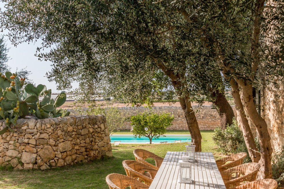 Diseño de jardín mediterráneo grande en verano en patio delantero con muro de contención, exposición total al sol y adoquines de piedra natural