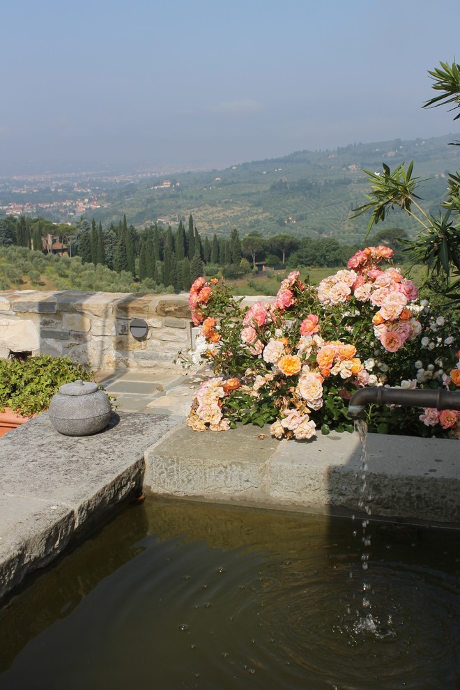 Foto di un grande giardino country esposto in pieno sole davanti casa in estate con fontane e pavimentazioni in pietra naturale