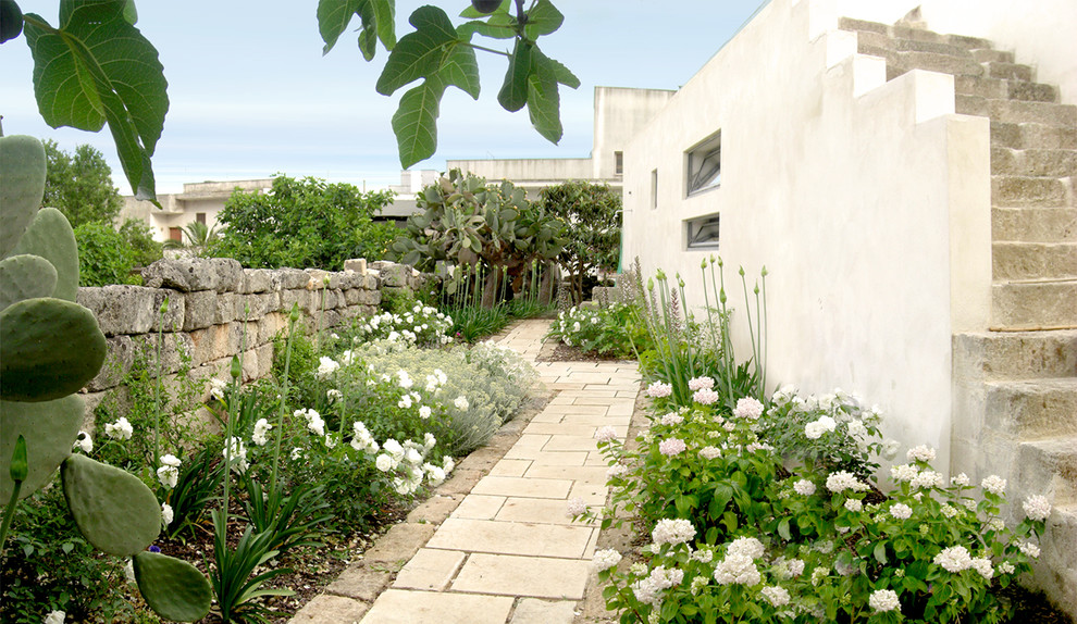 Esempio di un giardino mediterraneo esposto in pieno sole con pavimentazioni in pietra naturale e scale