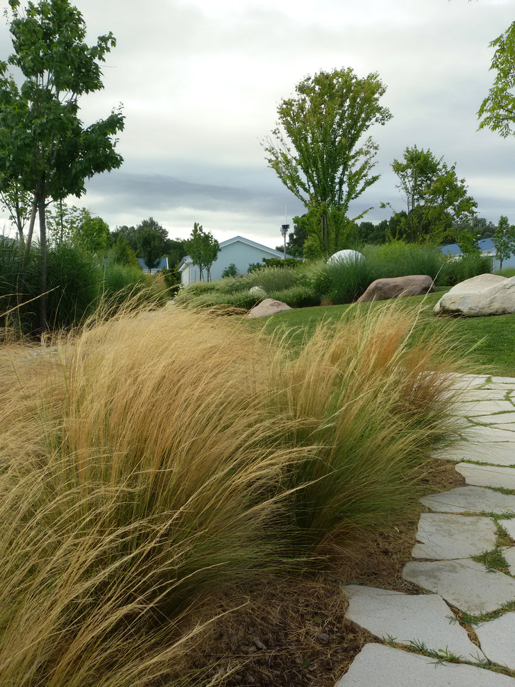 Idee per un grande giardino xeriscape mediterraneo esposto in pieno sole in estate con pavimentazioni in pietra naturale