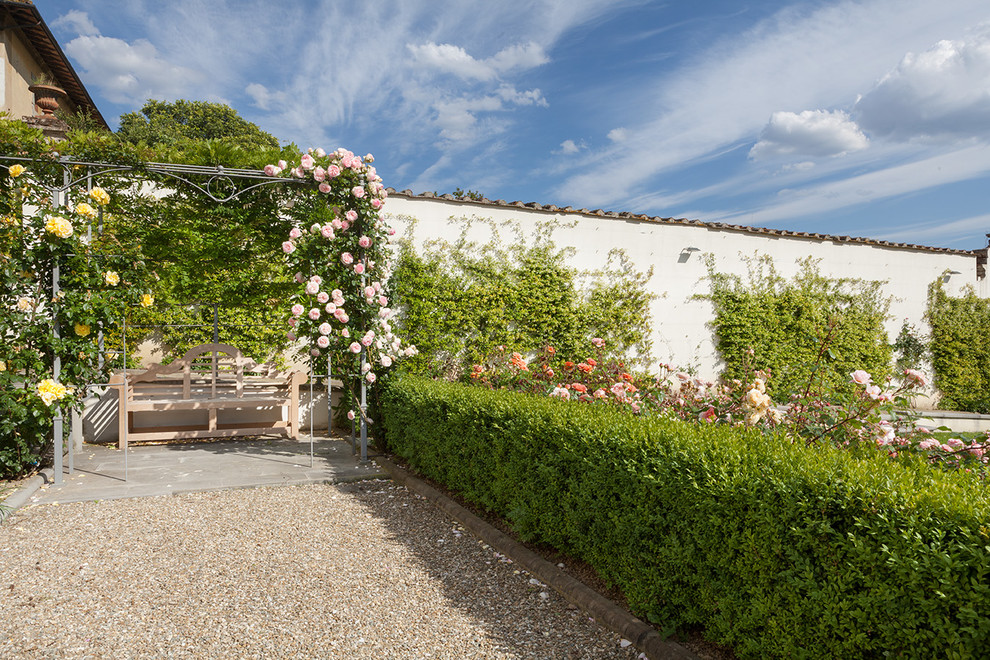 Aménagement d'un grand jardin latéral classique l'été avec une exposition ensoleillée et du gravier.