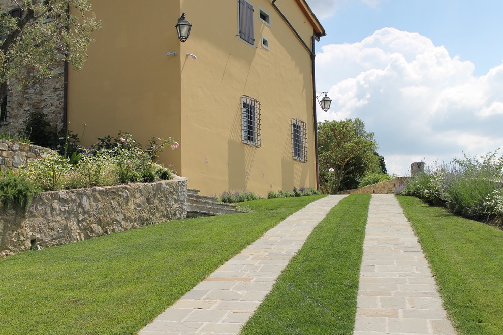 Esempio di un grande giardino country esposto in pieno sole davanti casa in estate con un muro di contenimento e pavimentazioni in pietra naturale