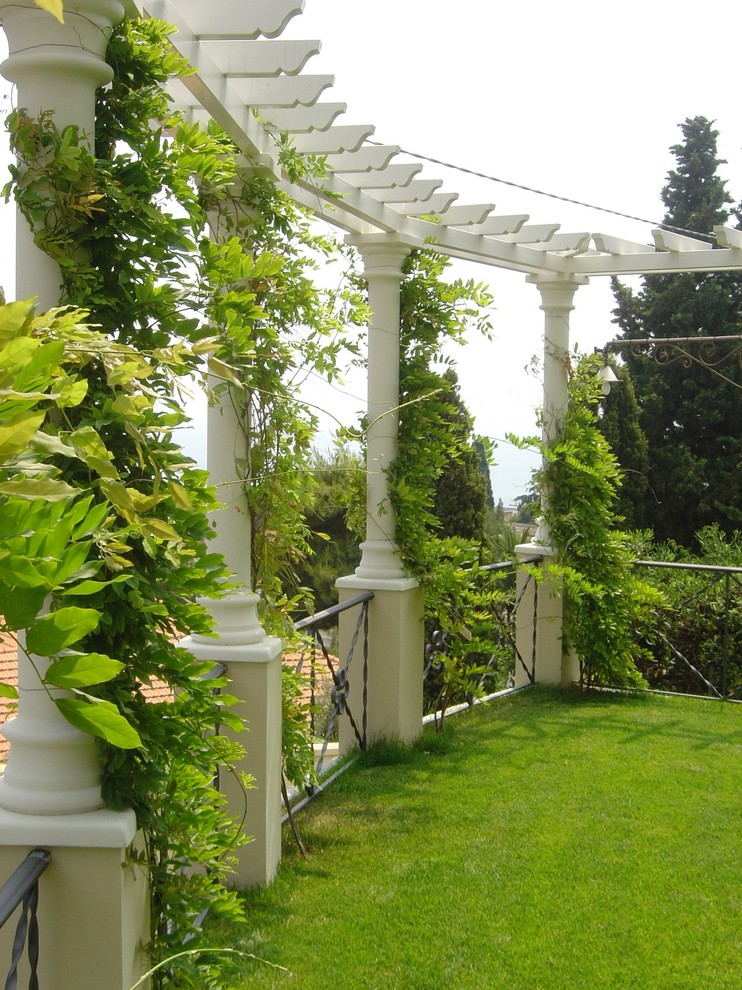 Inredning av en klassisk mycket stor formell trädgård i full sol framför huset på sommaren, med en vertikal trädgård och naturstensplattor