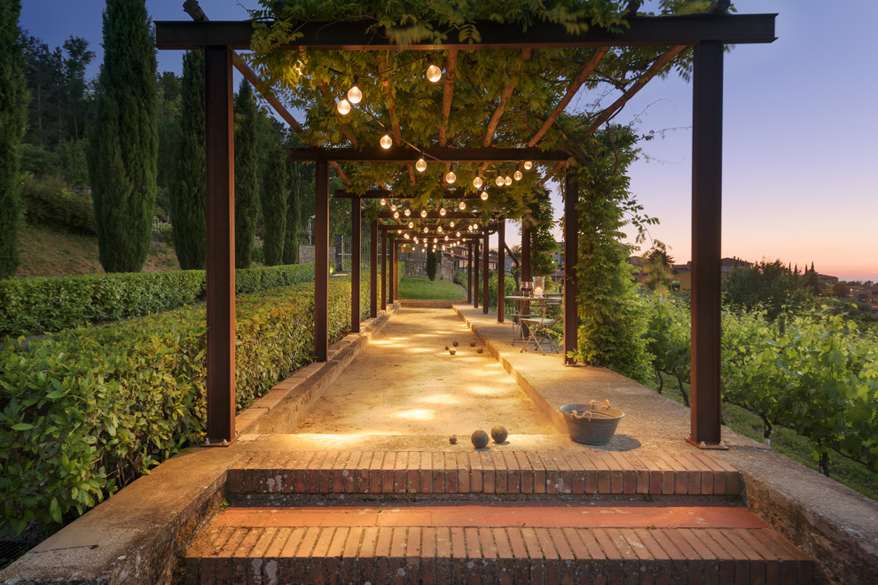 This is an example of a mediterranean backyard concrete paver outdoor sport court in Florence with a pergola.