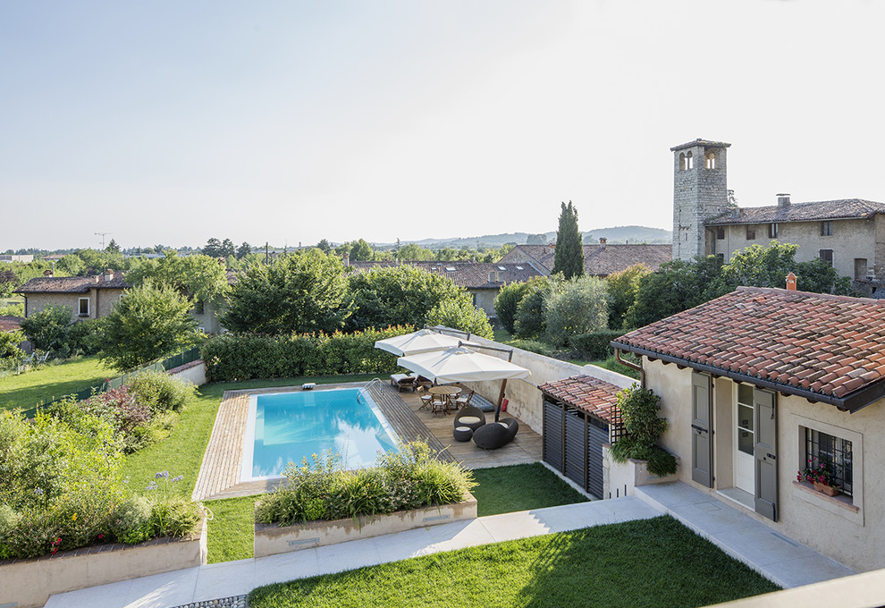 Inspiration for a mid-sized farmhouse front yard landscaping in Milan with decking.