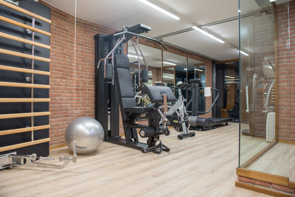 Multifunktionaler, Mittelgroßer Industrial Fitnessraum mit oranger Wandfarbe und hellem Holzboden in Barcelona
