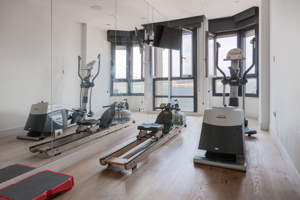 Small modern multi-use home gym in Bilbao with white walls and medium hardwood flooring.