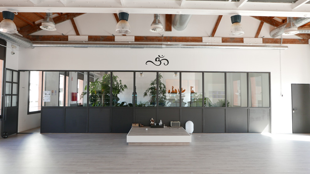 Großer Industrial Yogaraum mit weißer Wandfarbe, hellem Holzboden und grauem Boden in Sonstige