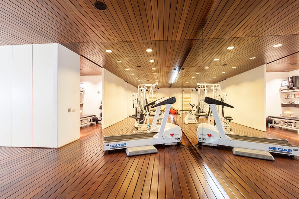 Multifunktionaler, Großer Moderner Fitnessraum mit weißer Wandfarbe und dunklem Holzboden in Madrid