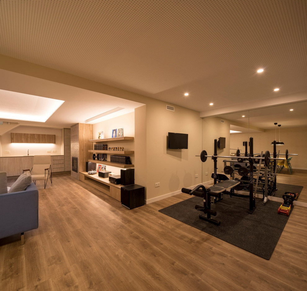 Multifunktionaler, Großer Moderner Fitnessraum mit beiger Wandfarbe, Laminat, braunem Boden und eingelassener Decke in Sonstige