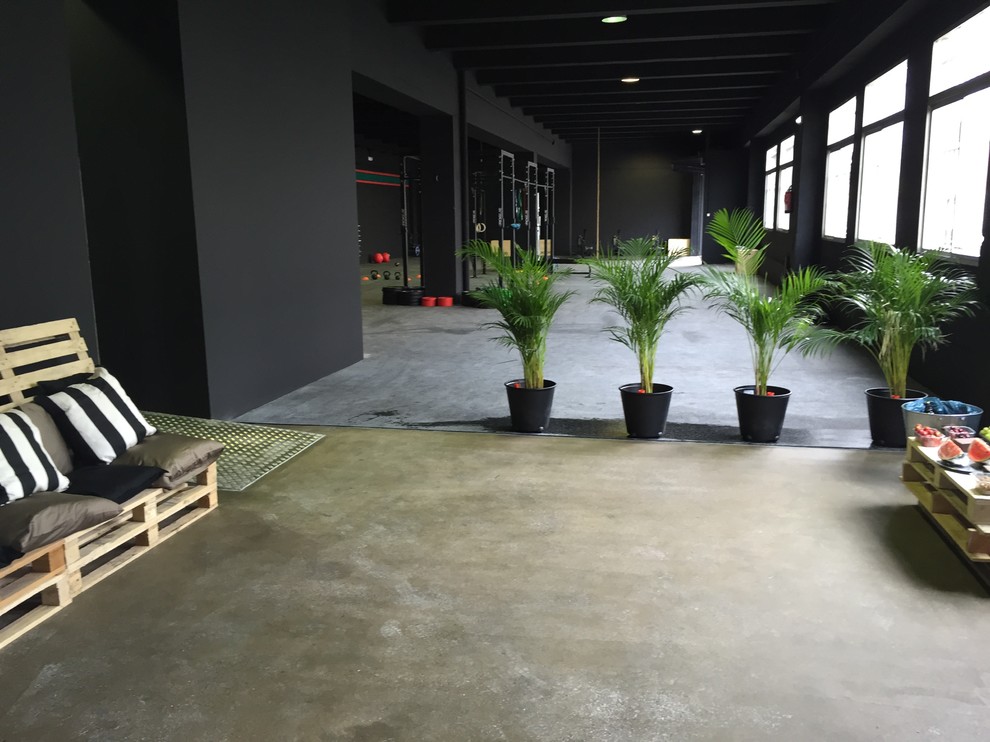 Geräumiger, Multifunktionaler Industrial Fitnessraum mit schwarzer Wandfarbe und Betonboden in Sonstige