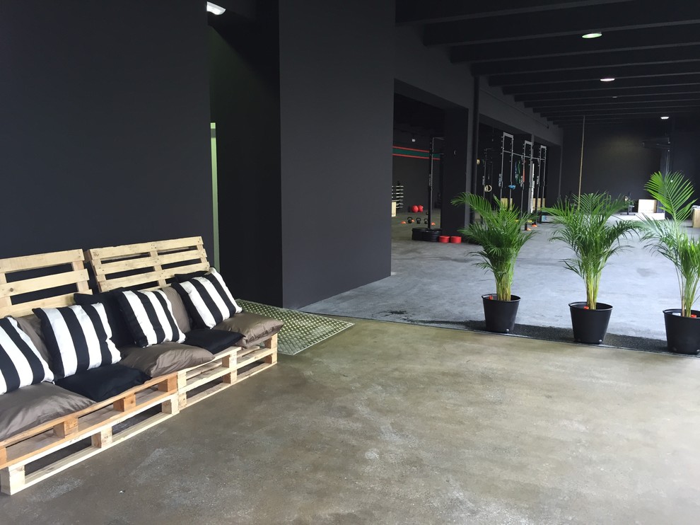 Geräumiger, Multifunktionaler Industrial Fitnessraum mit schwarzer Wandfarbe und Betonboden in Sonstige