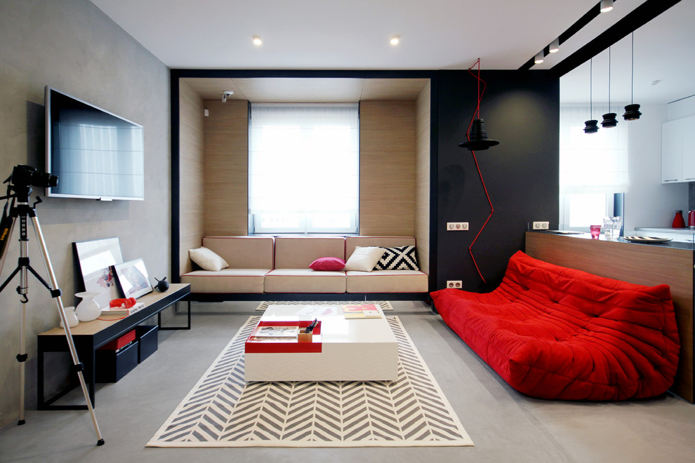 他の地域にあるコンテンポラリースタイルのおしゃれな応接間 (ベージュの壁、コンクリートの床、壁掛け型テレビ、赤いソファ) の写真