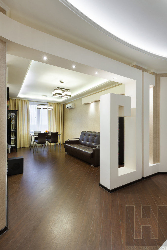 Idée de décoration pour un salon design de taille moyenne et ouvert avec un mur beige, un sol en bois brun, un téléviseur fixé au mur et un sol marron.