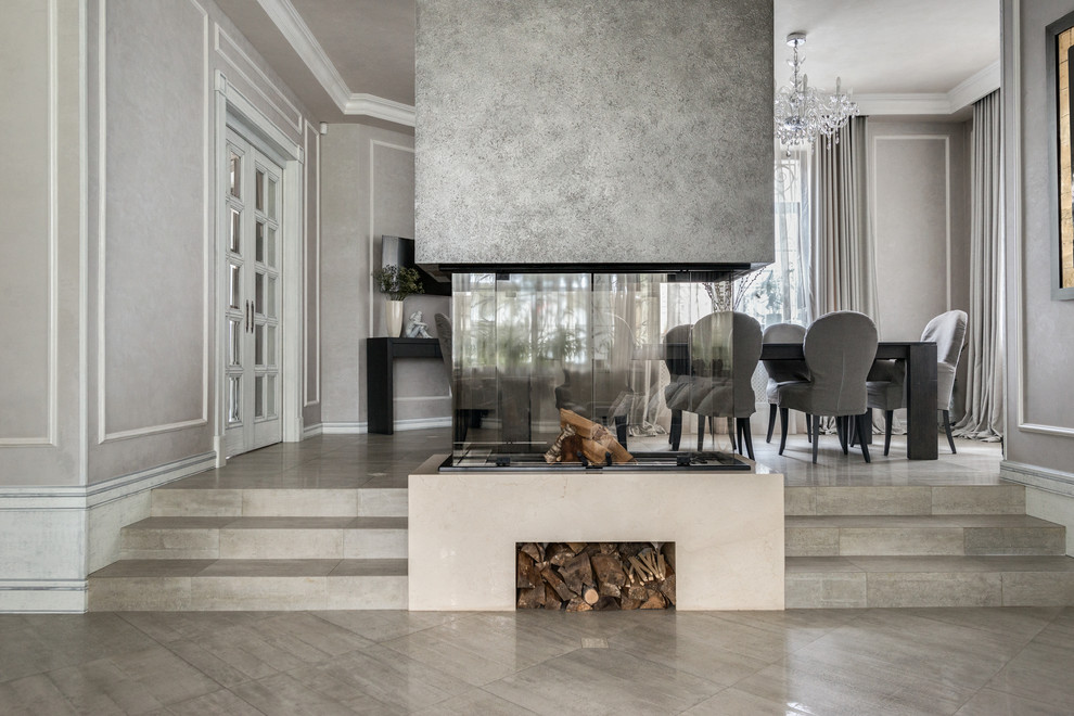 Aménagement d'un salon classique ouvert avec un mur gris, une cheminée double-face et un sol gris.