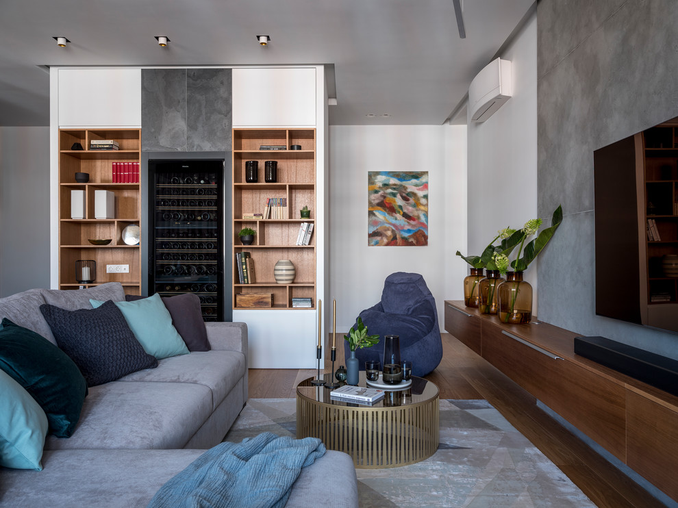 Ejemplo de salón para visitas actual con paredes blancas, suelo de madera en tonos medios, televisor colgado en la pared y suelo marrón