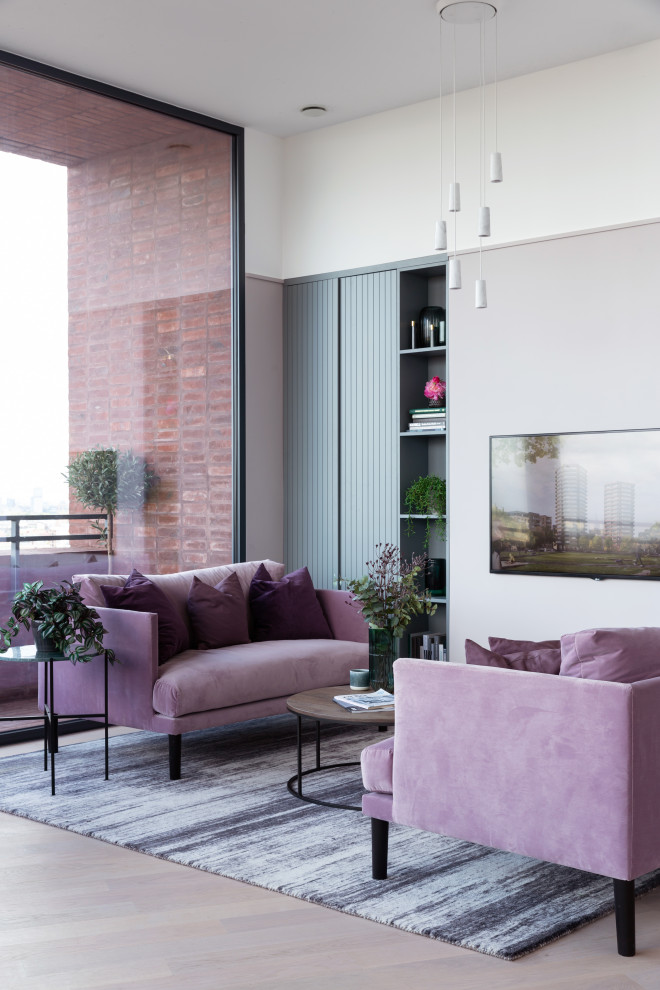 На фото: гостиная комната в современном стиле с белыми стенами, светлым паркетным полом, телевизором на стене и бежевым полом с