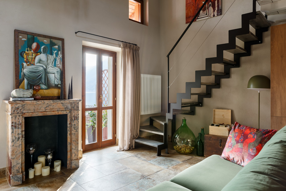 Exemple d'un petit salon mansardé ou avec mezzanine méditerranéen avec un sol en carrelage de porcelaine, une cheminée standard et un téléviseur fixé au mur.