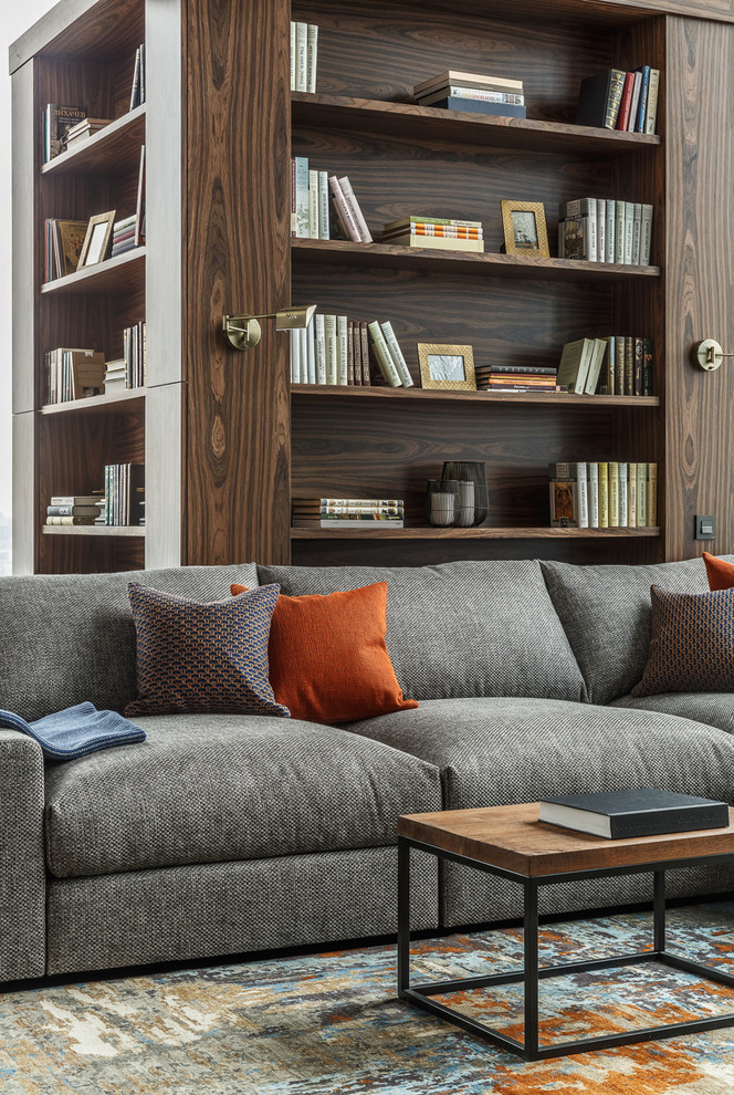 Ejemplo de biblioteca en casa abierta actual de tamaño medio sin chimenea y televisor con paredes grises, suelo de madera en tonos medios y suelo marrón