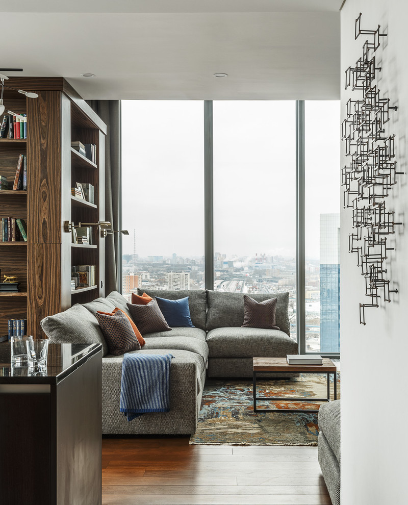 Идея дизайна: открытая, объединенная гостиная комната среднего размера в современном стиле с с книжными шкафами и полками, серыми стенами, паркетным полом среднего тона и коричневым полом без камина, телевизора