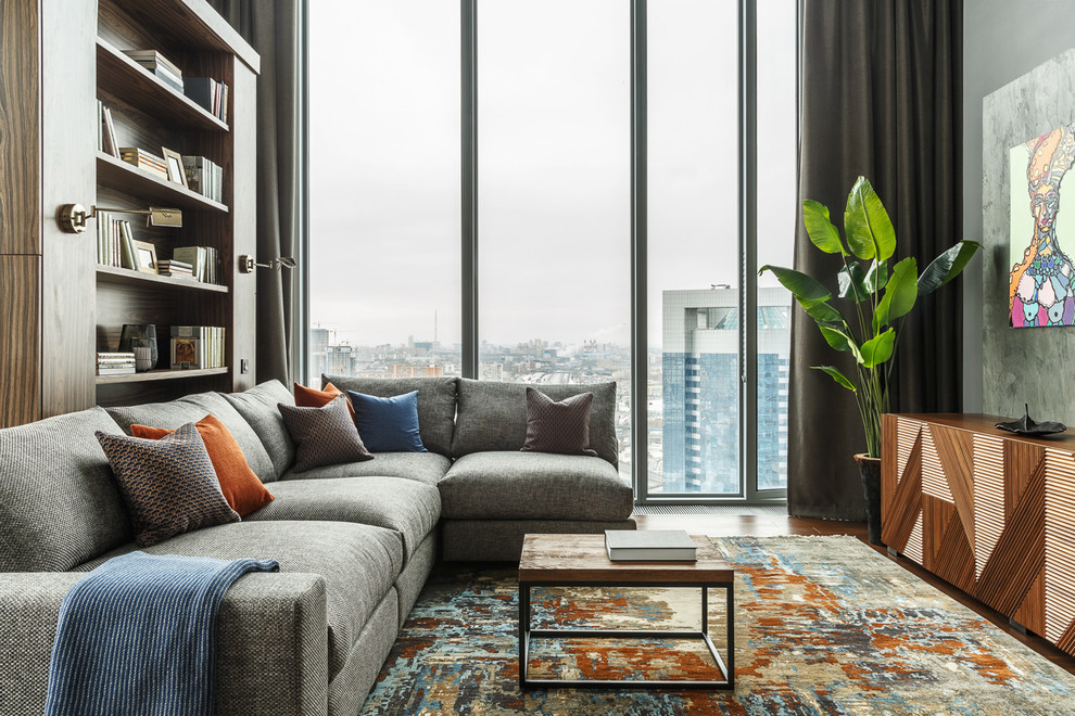 Cette image montre un salon design de taille moyenne et ouvert avec une bibliothèque ou un coin lecture, un mur gris, aucune cheminée, aucun téléviseur, moquette et un sol multicolore.