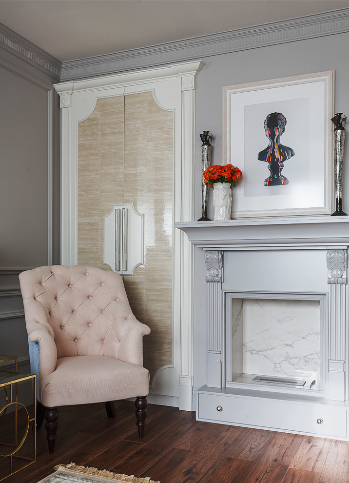 Modelo de salón para visitas clásico renovado con paredes grises, suelo de madera en tonos medios y todas las chimeneas