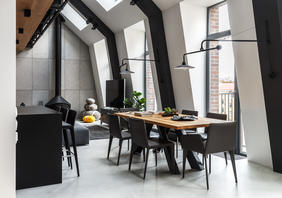 Exemple d'une salle à manger tendance de taille moyenne avec un mur blanc, sol en béton ciré, cheminée suspendue, un manteau de cheminée en métal et un sol gris.