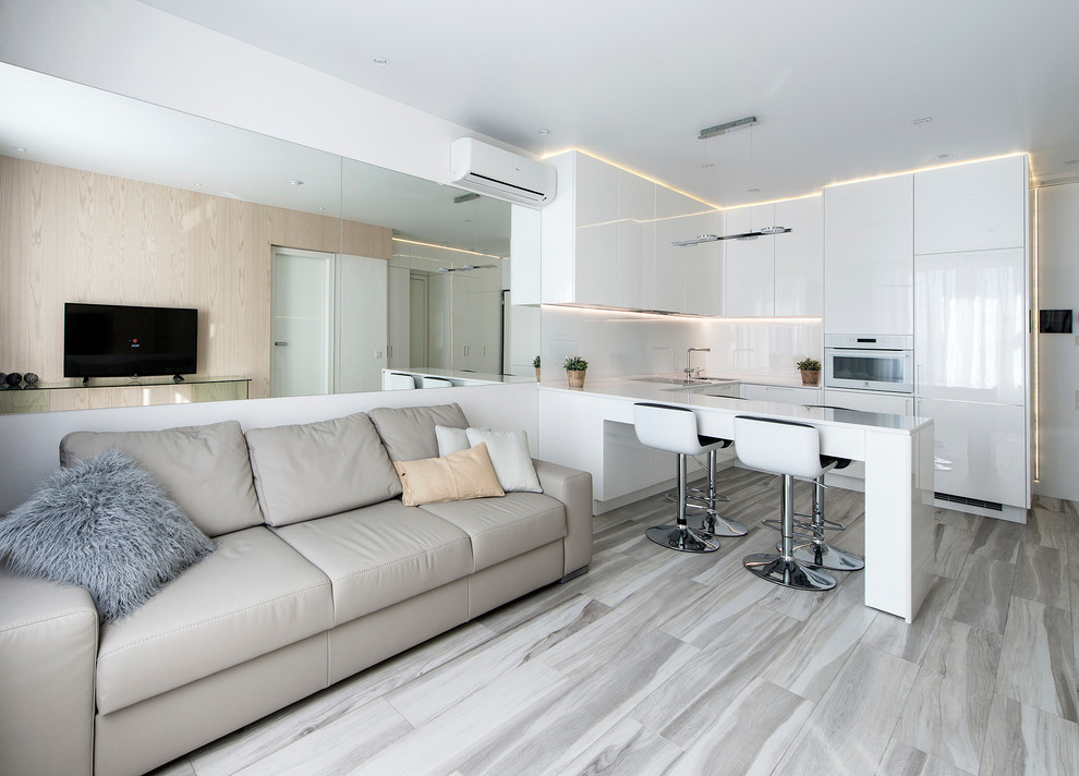 Modelo de salón para visitas abierto actual pequeño con paredes blancas, suelo de madera clara y televisor colgado en la pared